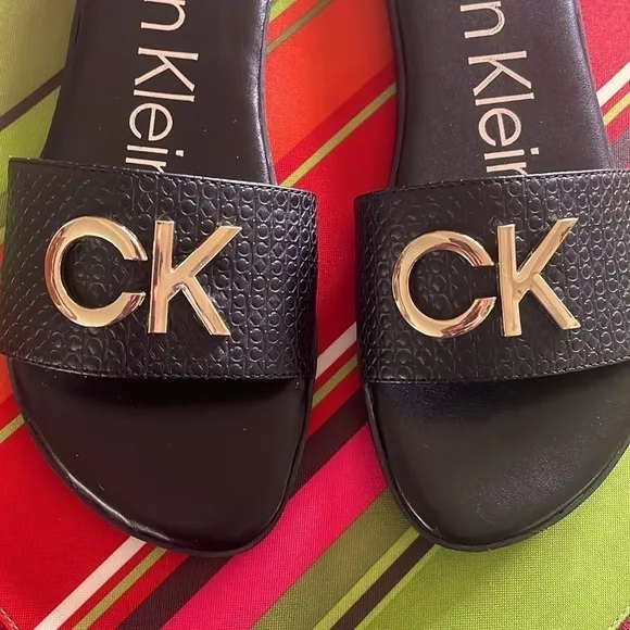 Brand New Calvin Klein Black Large Strap Sandals Flats w/ Gold Tone Metal Logo